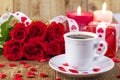 Cup with coffee in front of bouquet of red roses Royalty Free Stock Photo